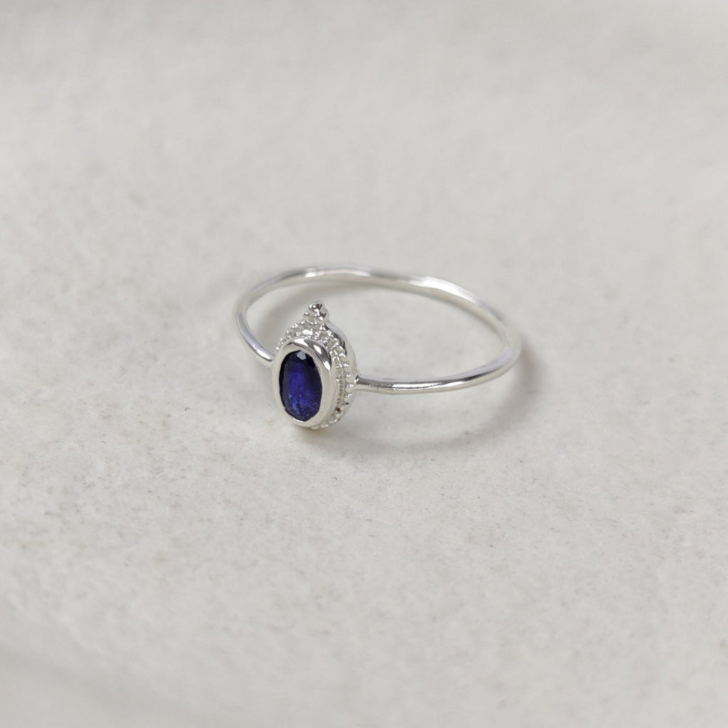 Silver ring with a dark blue gemstone on a white background