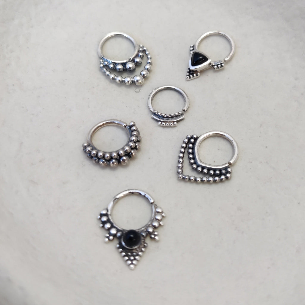 A collection of silver septum jewelry featuring intricate dotted details and onyx gemstones, displayed to showcase their unique designs.