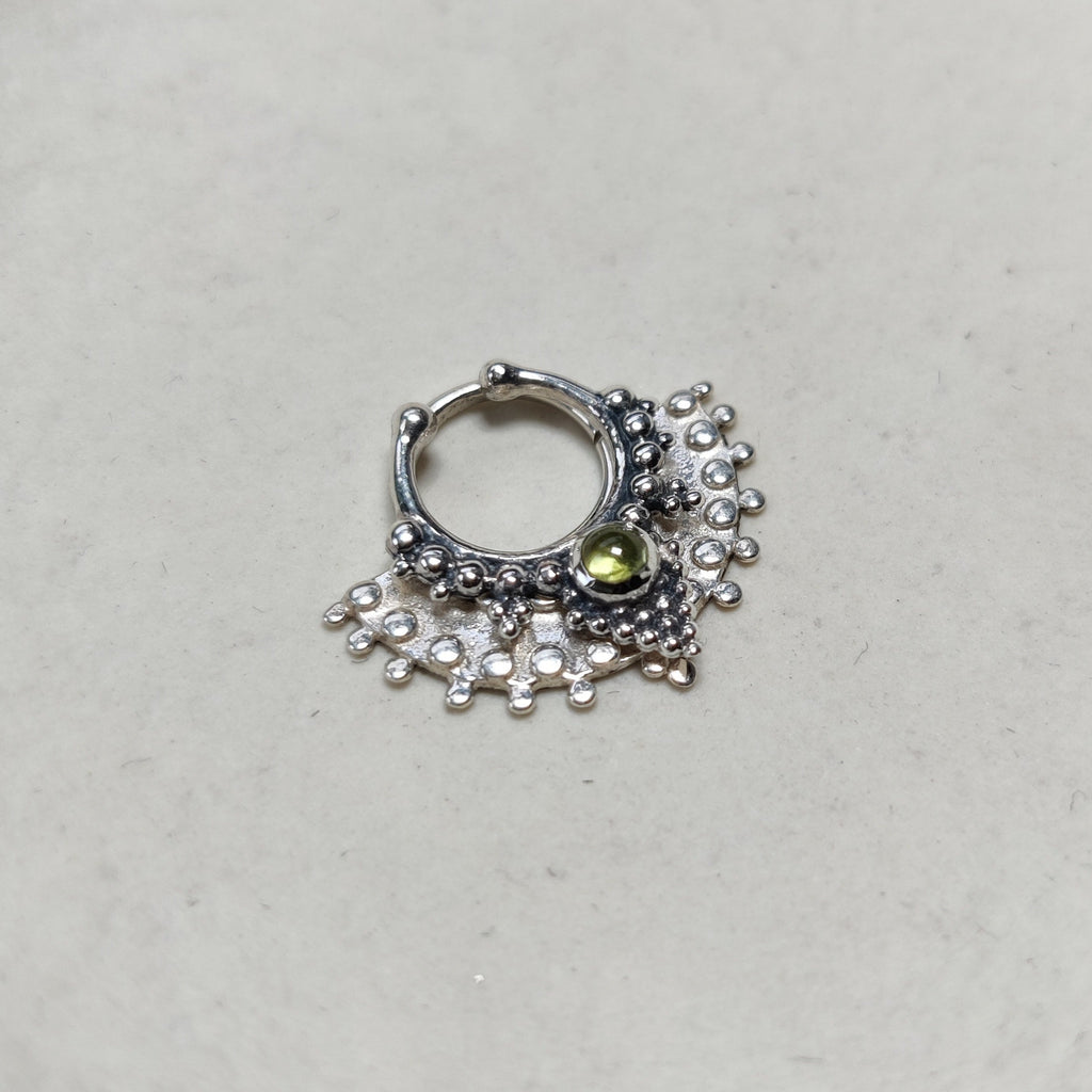 A large fan septum and a fake septum nose ring with green gemstone, styled together for a layered look.