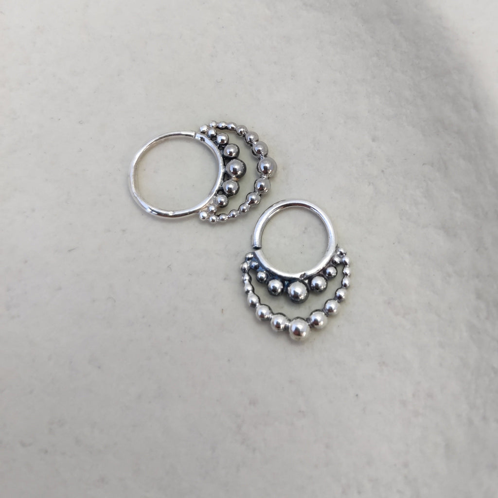 Ornamental silver septum rings with intricate detailing, showcased from various angles, highlighting their layered design.