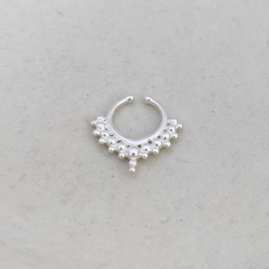 Silver nose ring with dotted details, displayed on light background.
