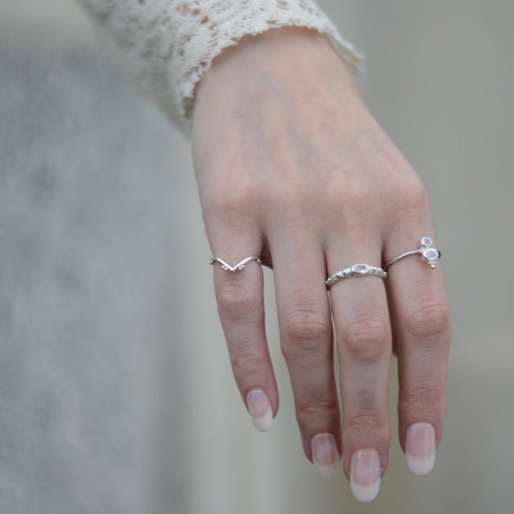 Hand wearing multiple silver rings with a blurred background.
