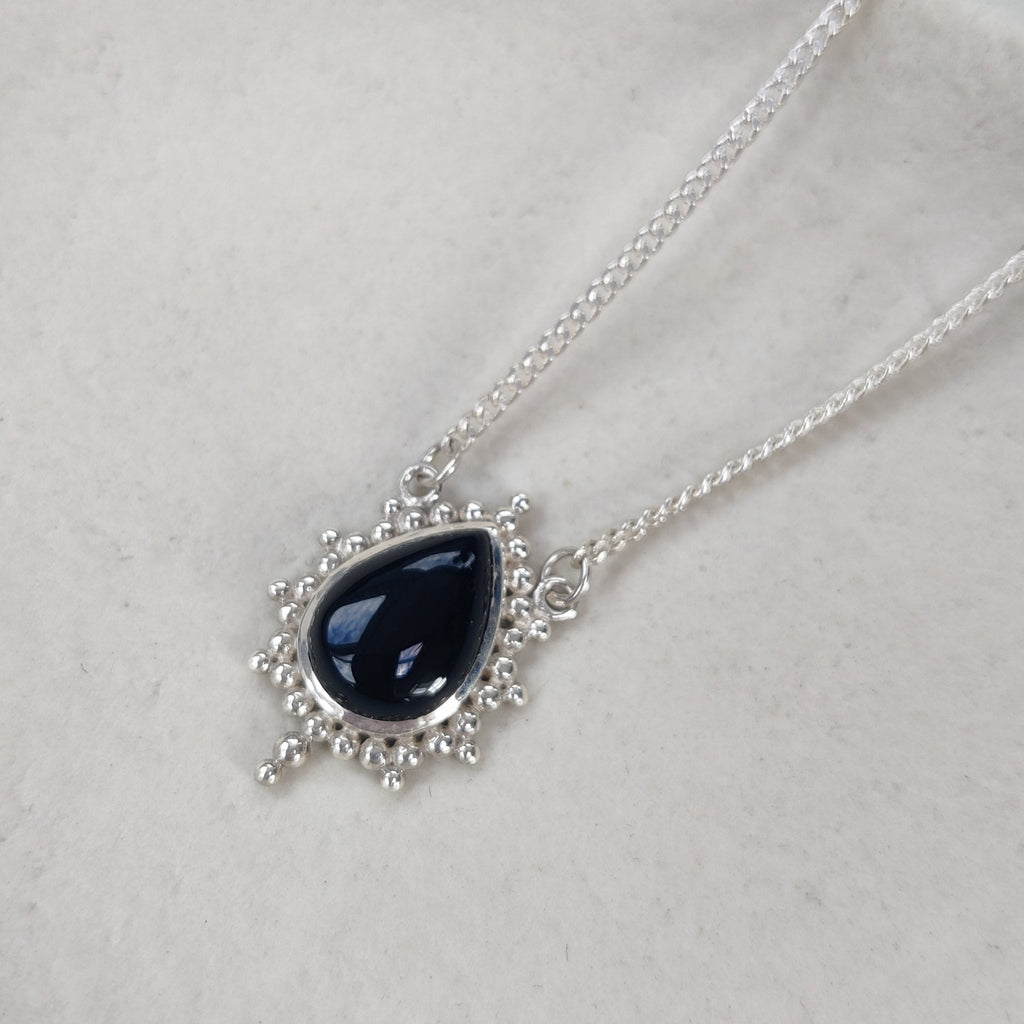 Necklace with a black teardrop pendant on a light background