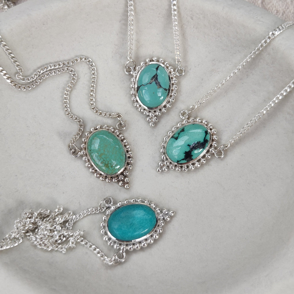 Silver necklaces set with turquoise stones on a white background
