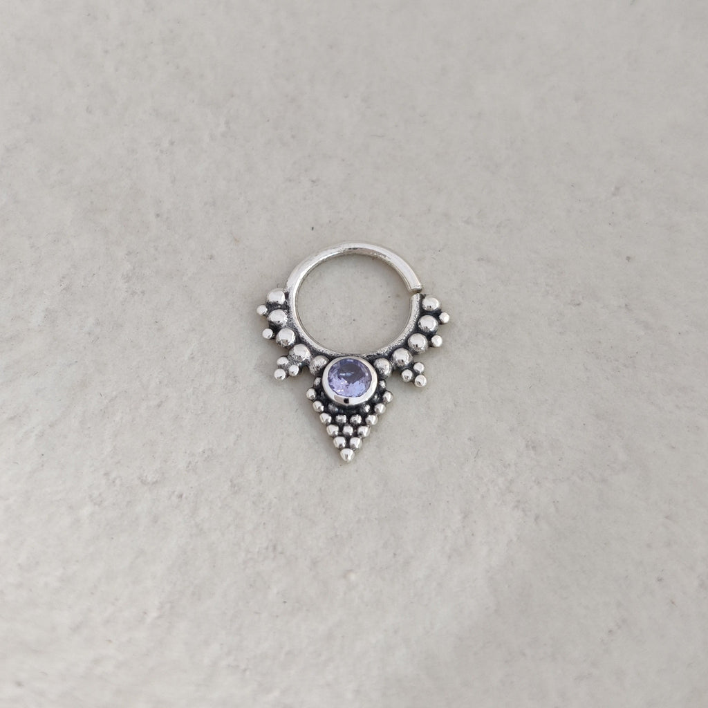 Silver nose ring with a purple gemstone on a white background