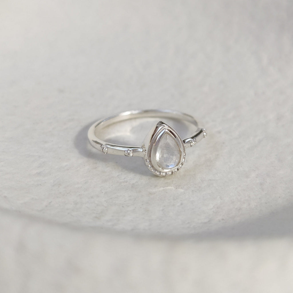 Silver ring with a moonstone on a white background.