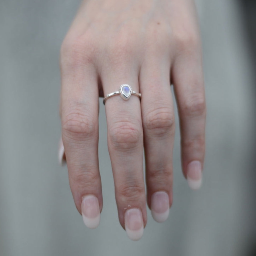 Hand wearing a drop-shaped moonstone silver ring.