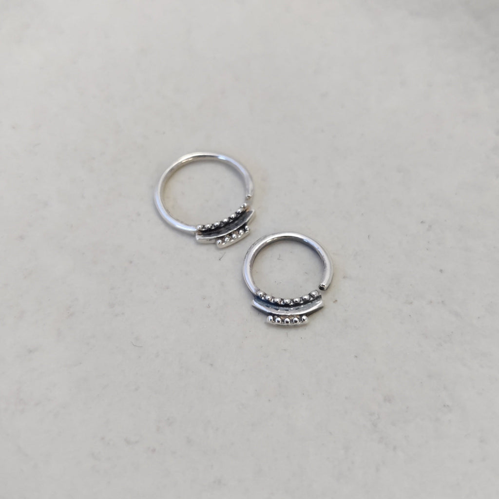 Dainty silver septum rings with intricate detailing, comparing the difference between 8mm and 10mm diameters and highlighting its unique design.