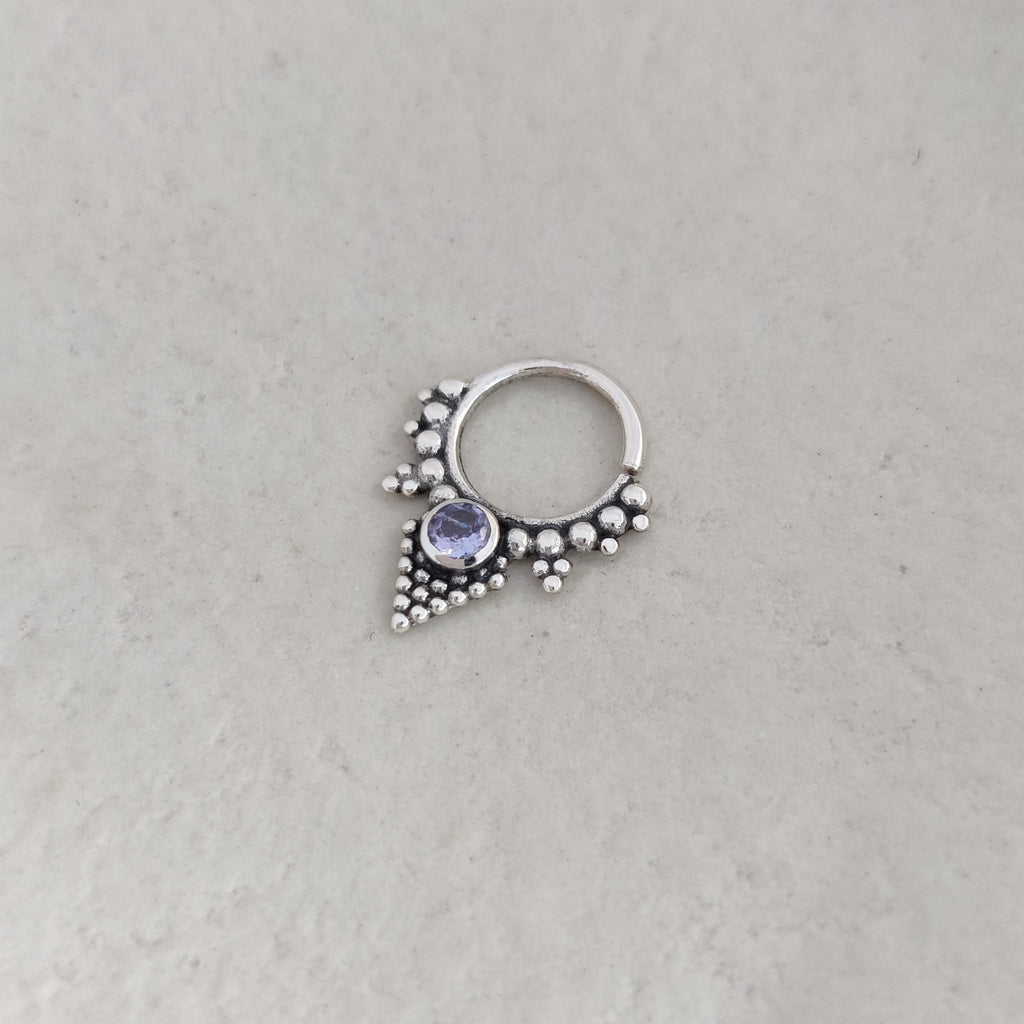 Silver ring with a purple gemstone on a light background