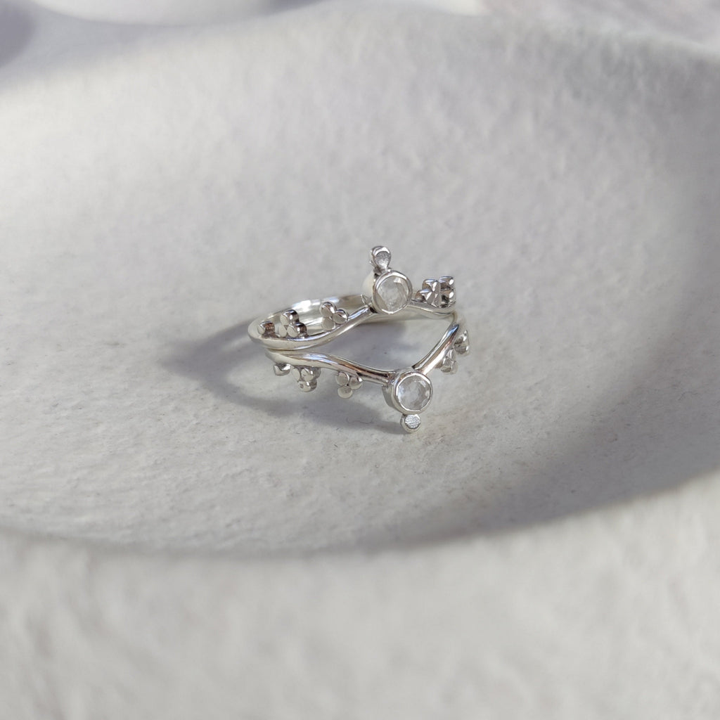 Two silver stacking rings with small moonstones on a textured white surface.