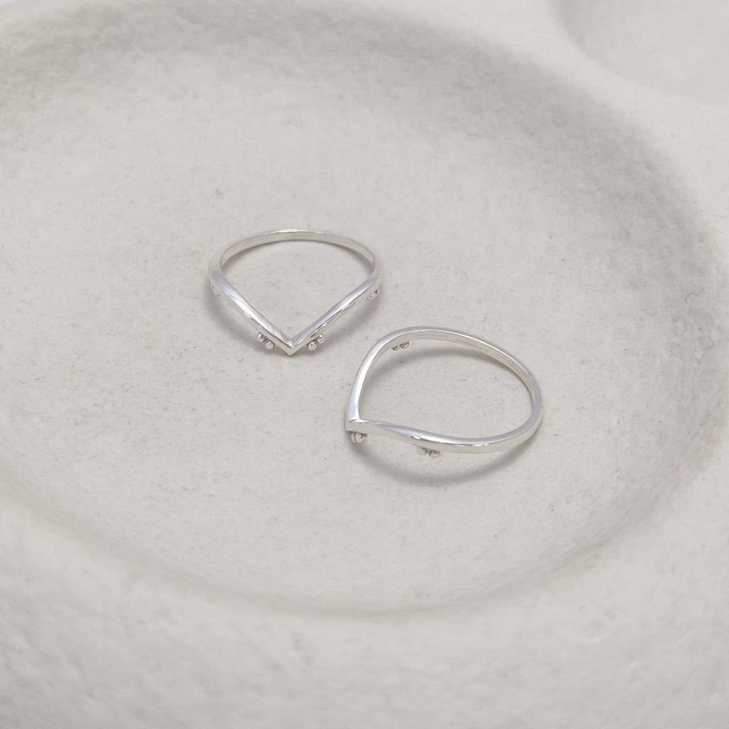 Silver stacking rings on a textured white surface.