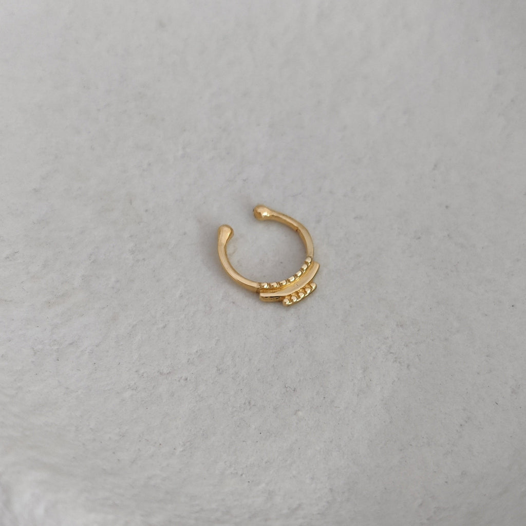 Gold fake nose ring on a textured white surface