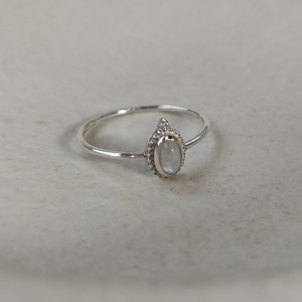 Silver ring with a tiny moonstone on a light surface