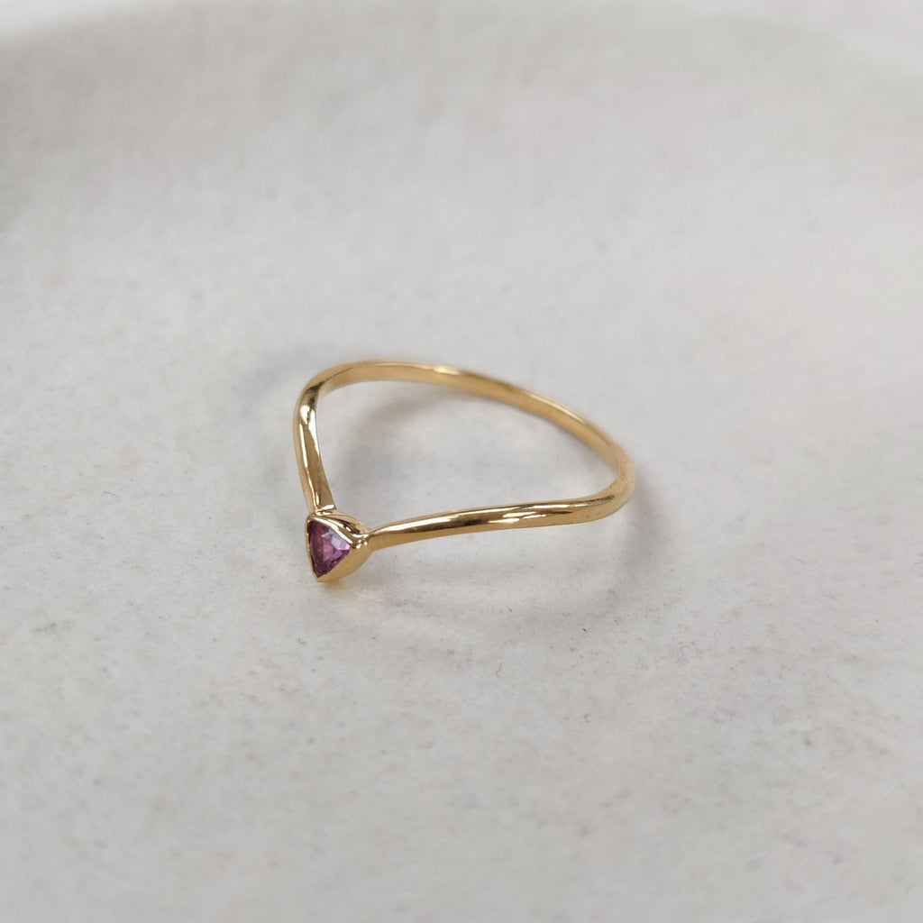 Gold ring with a pink gemstone on a light gray background