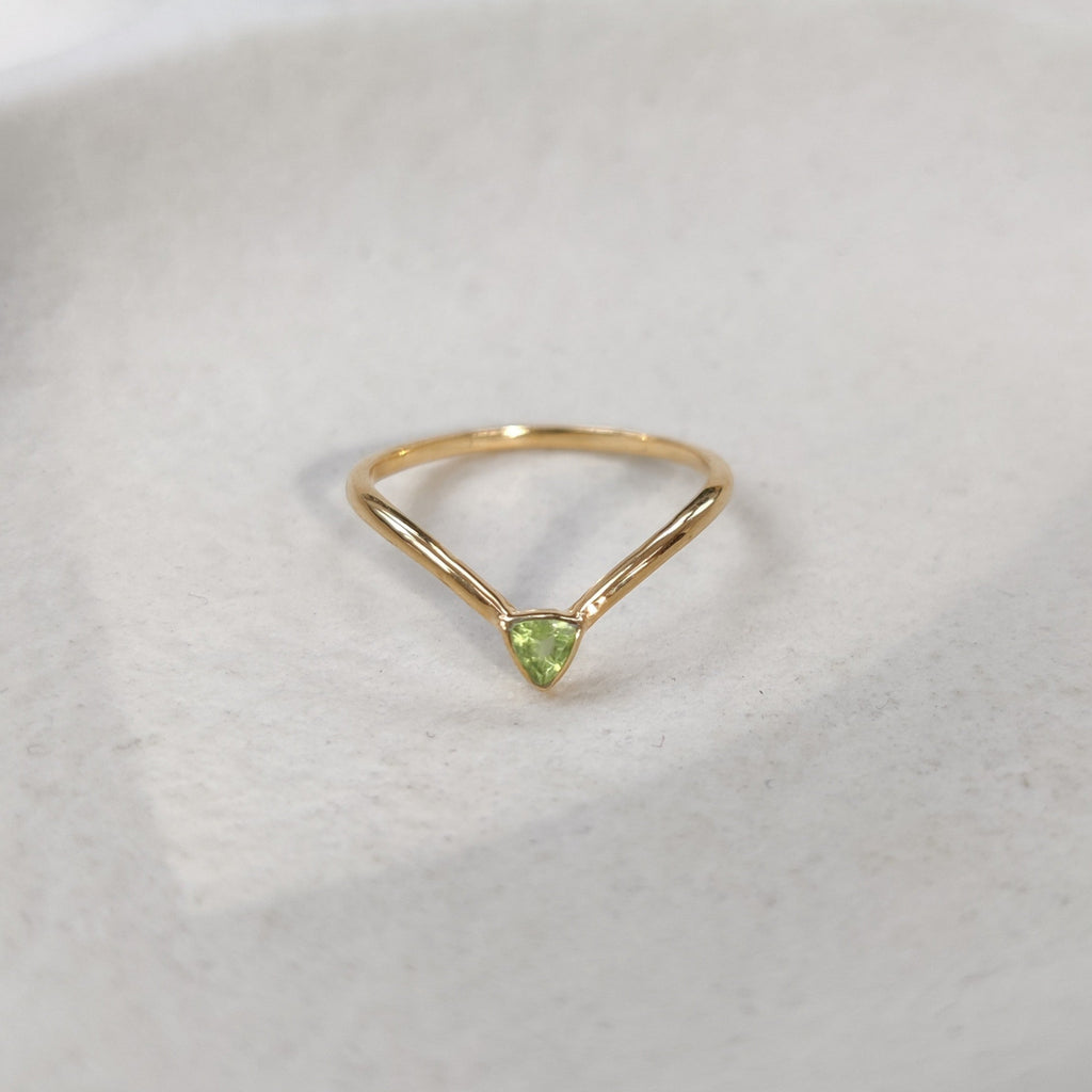 Gold ring with a green gemstone on a white fabric background