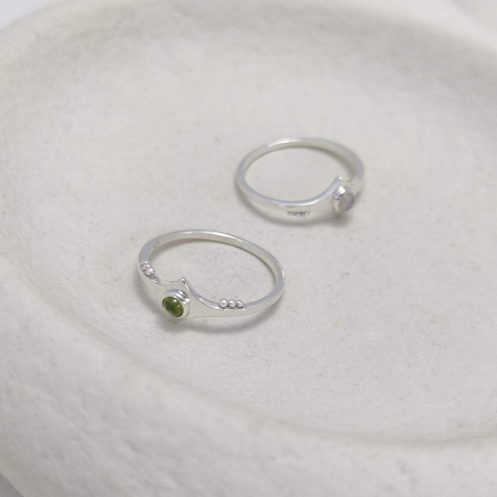 Two silver rings with gemstones on a white stone surface.