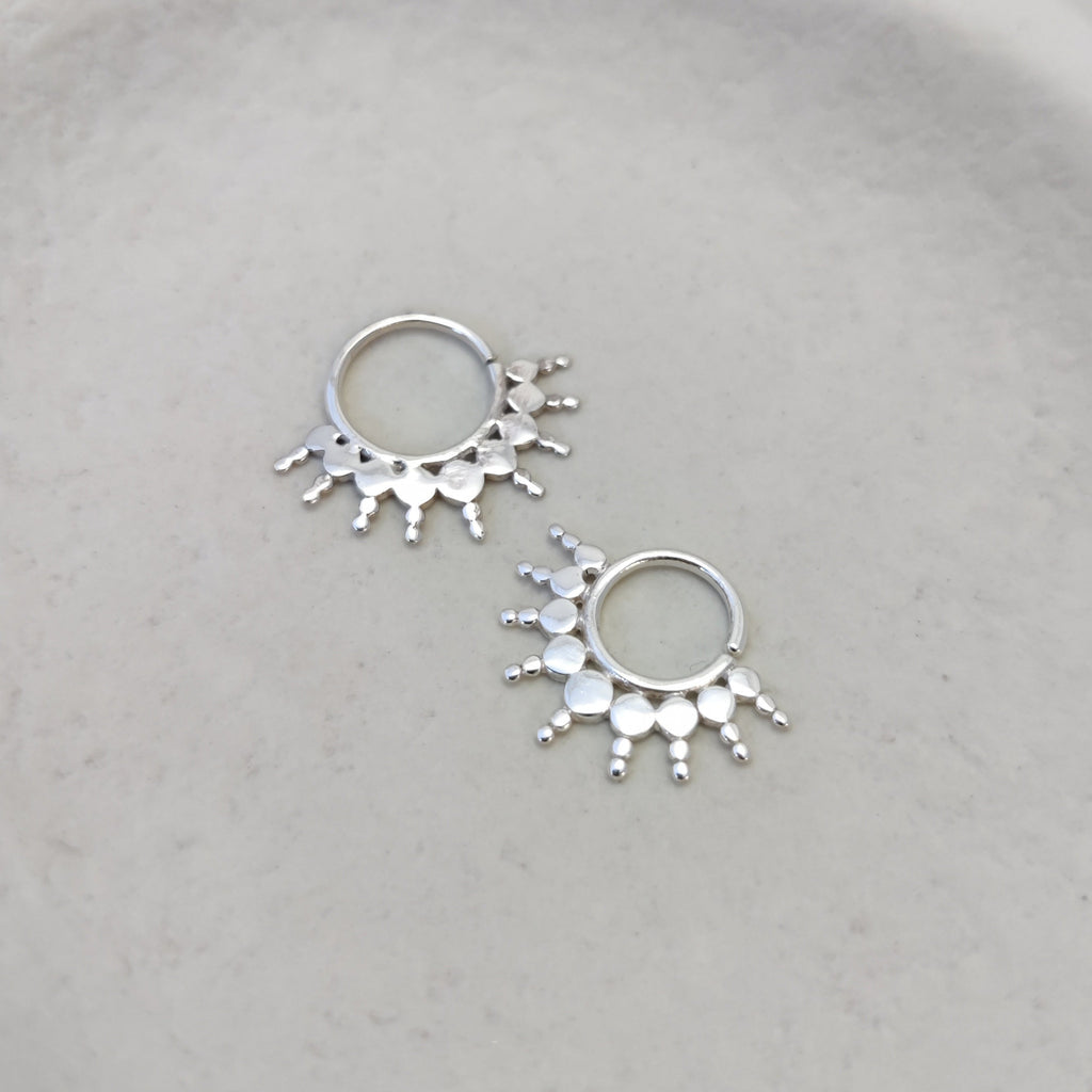 Ornamental large silver septum rings with flat design and intricate detailing.