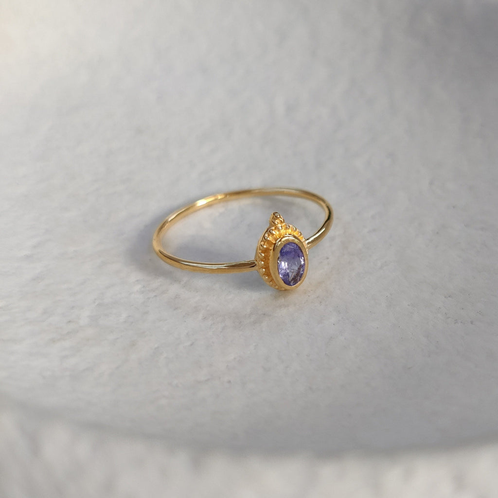 Gold ring with a tanzanite  gemstone on a textured white surface