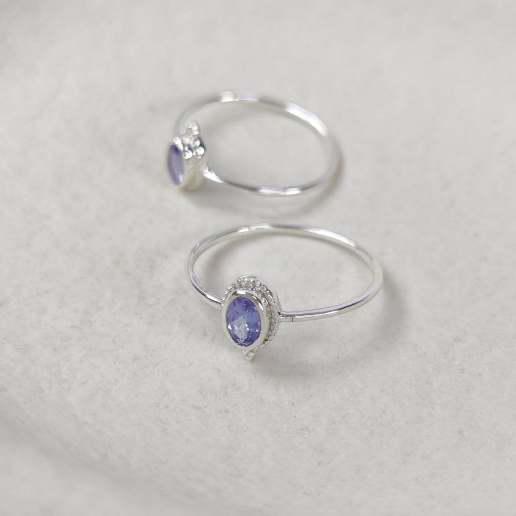 Two silver rings with tanzanite gemstones on a textured surface