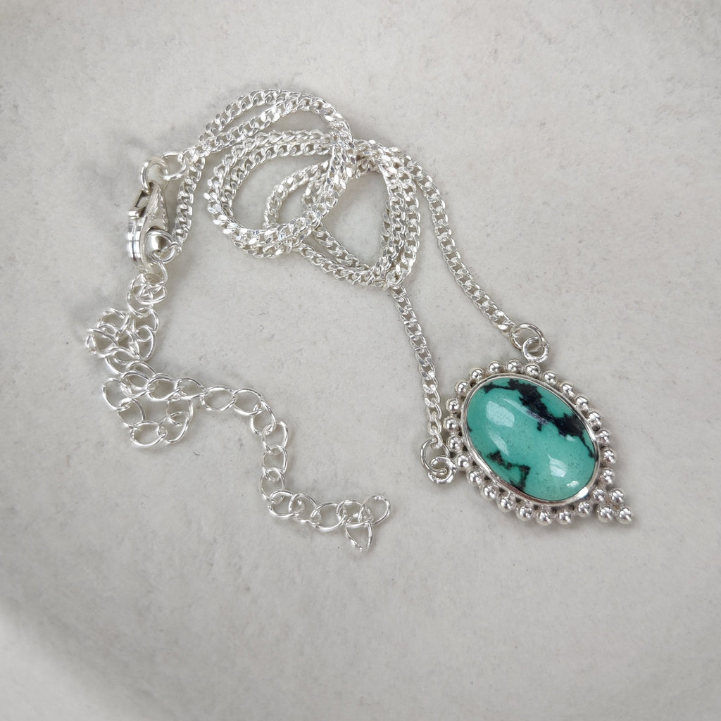 Necklace with a natural turquoise pendant on a white dish