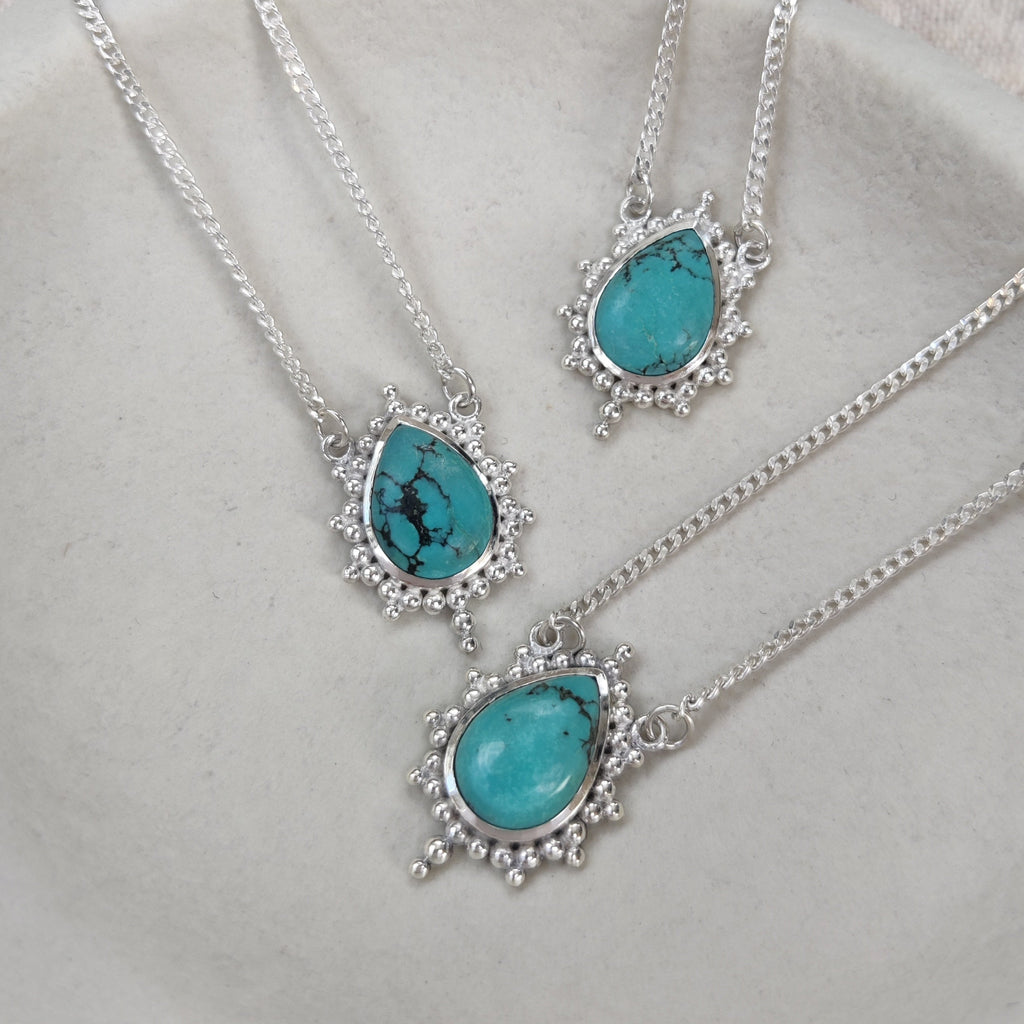 Turquoise necklaces with silver chain on a light gray background