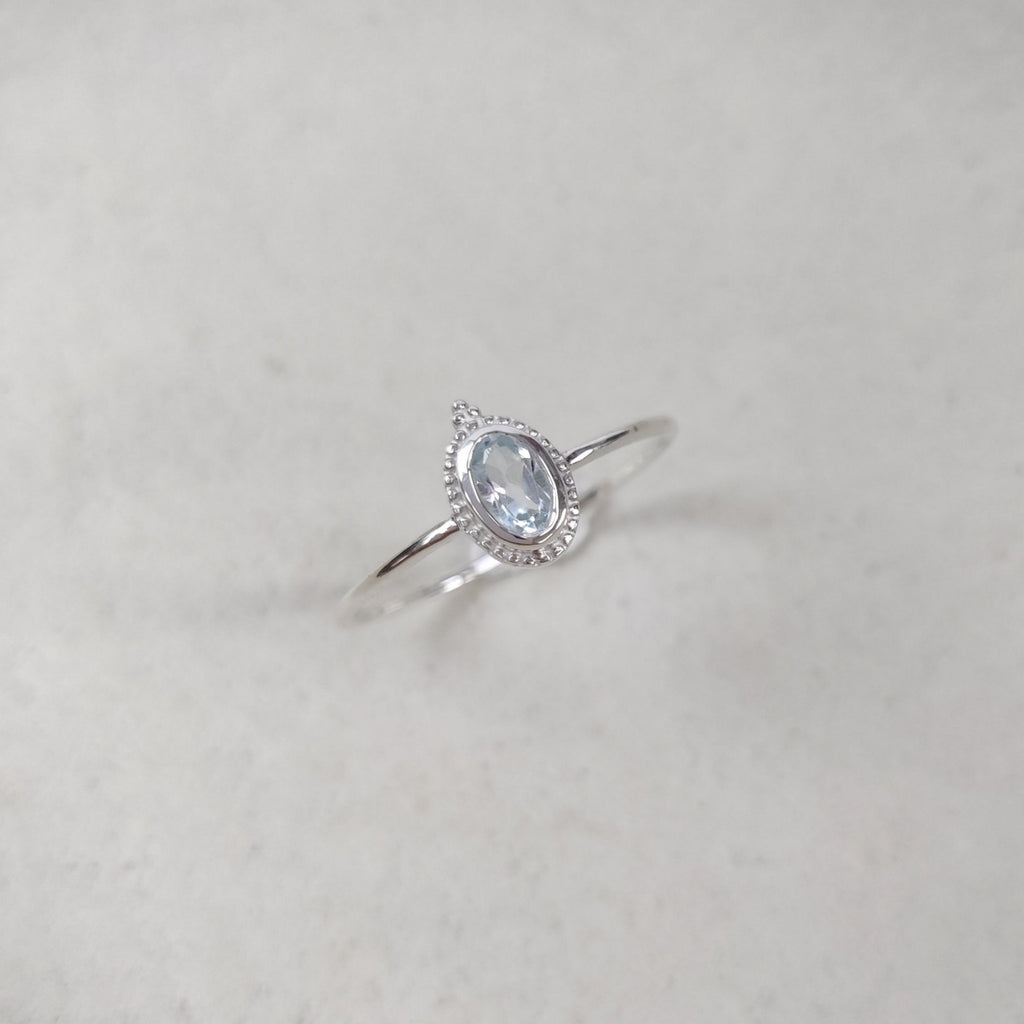 Silver ring with a blue topaz gemstone on a white background