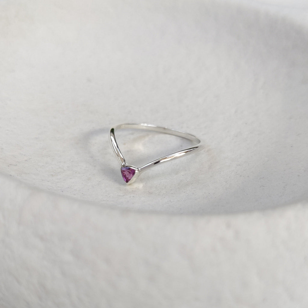 Silver ring with a purple gemstone on a textured white surface