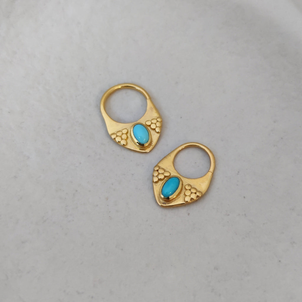 Close-up of gold septum nose rings with turquoise showcased from various angles, highlighting their intricate details and v-shape design.