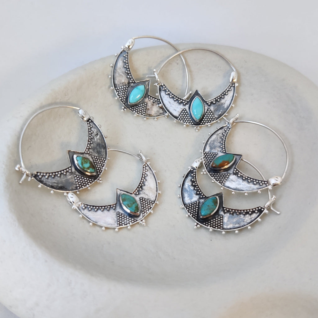 Three pairs of silver crescent hoop earrings with turquoise, displayed side by side to showcase the natural variations in turquoise shades.