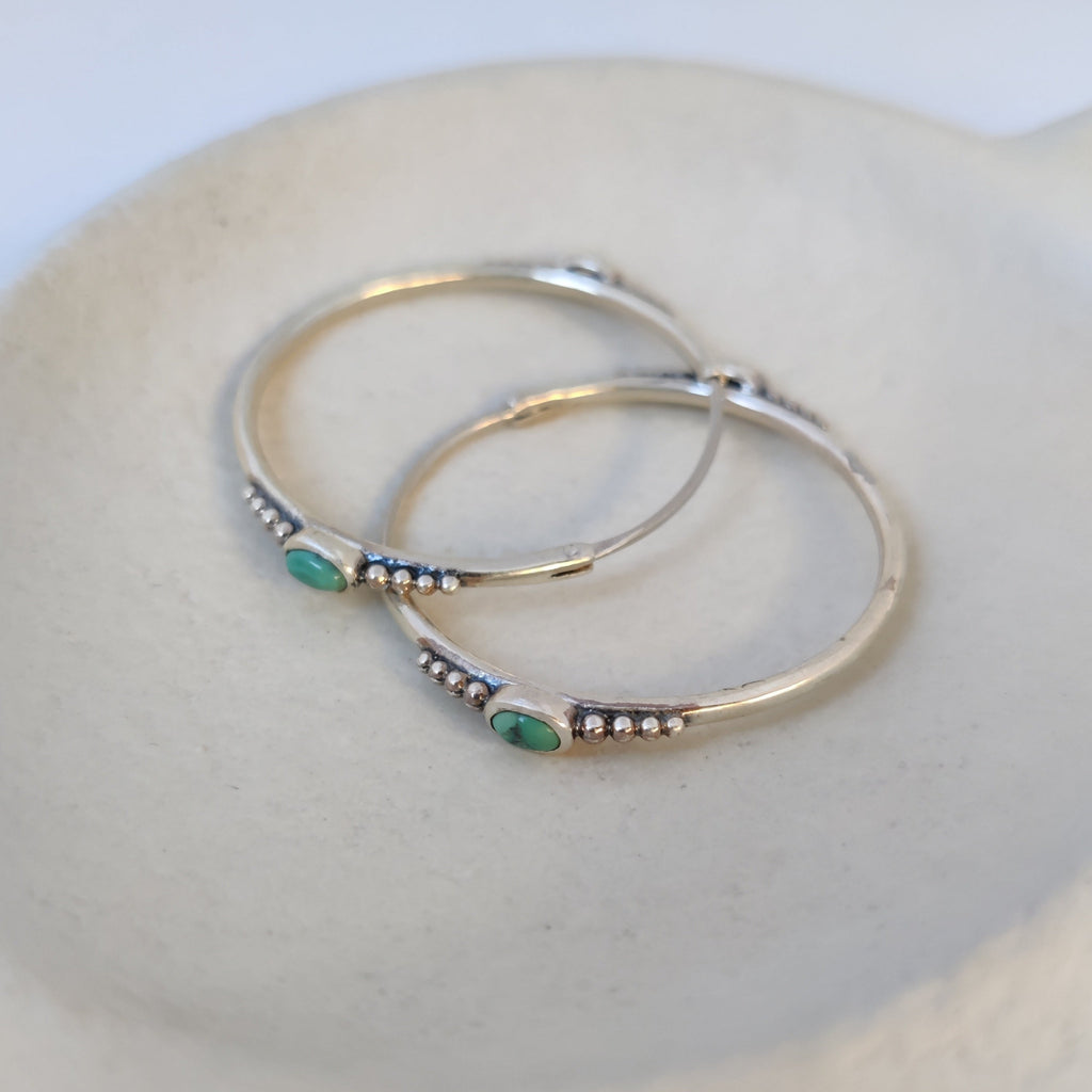 Unique silver hoop earrings featuring intricate dotted details vibrant turquoise gemstones.