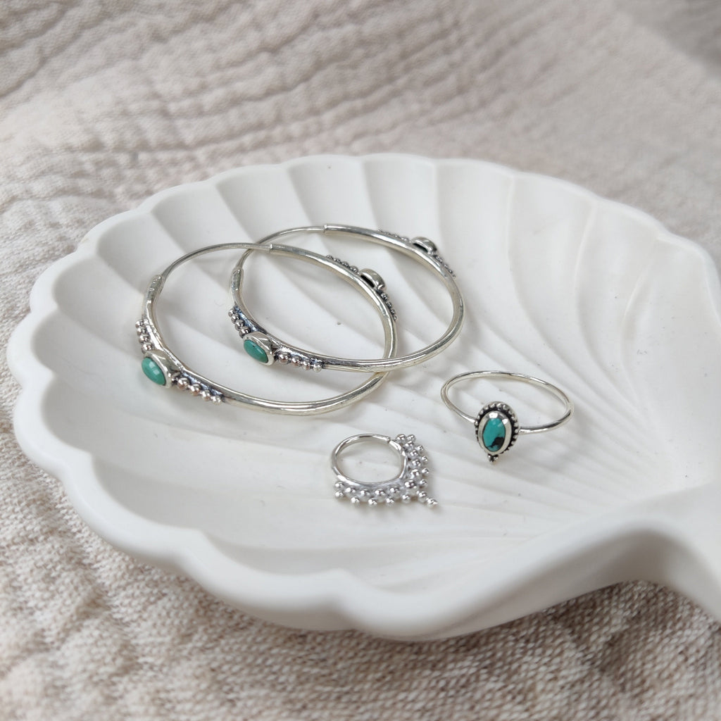 Silver earrings, ring and septum displayed on a jewelry plate.