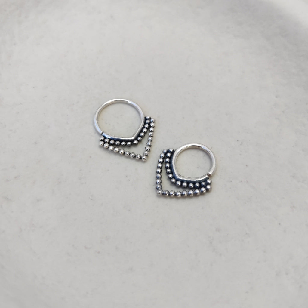 Ornamental silver septum rings with v-shaped design and intricate detailing, highlighting its unique design and craftsmanship.