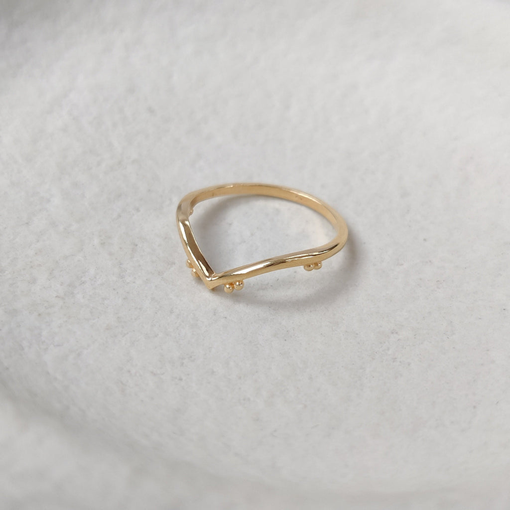 Gold ring on a textured white surface, side angle.