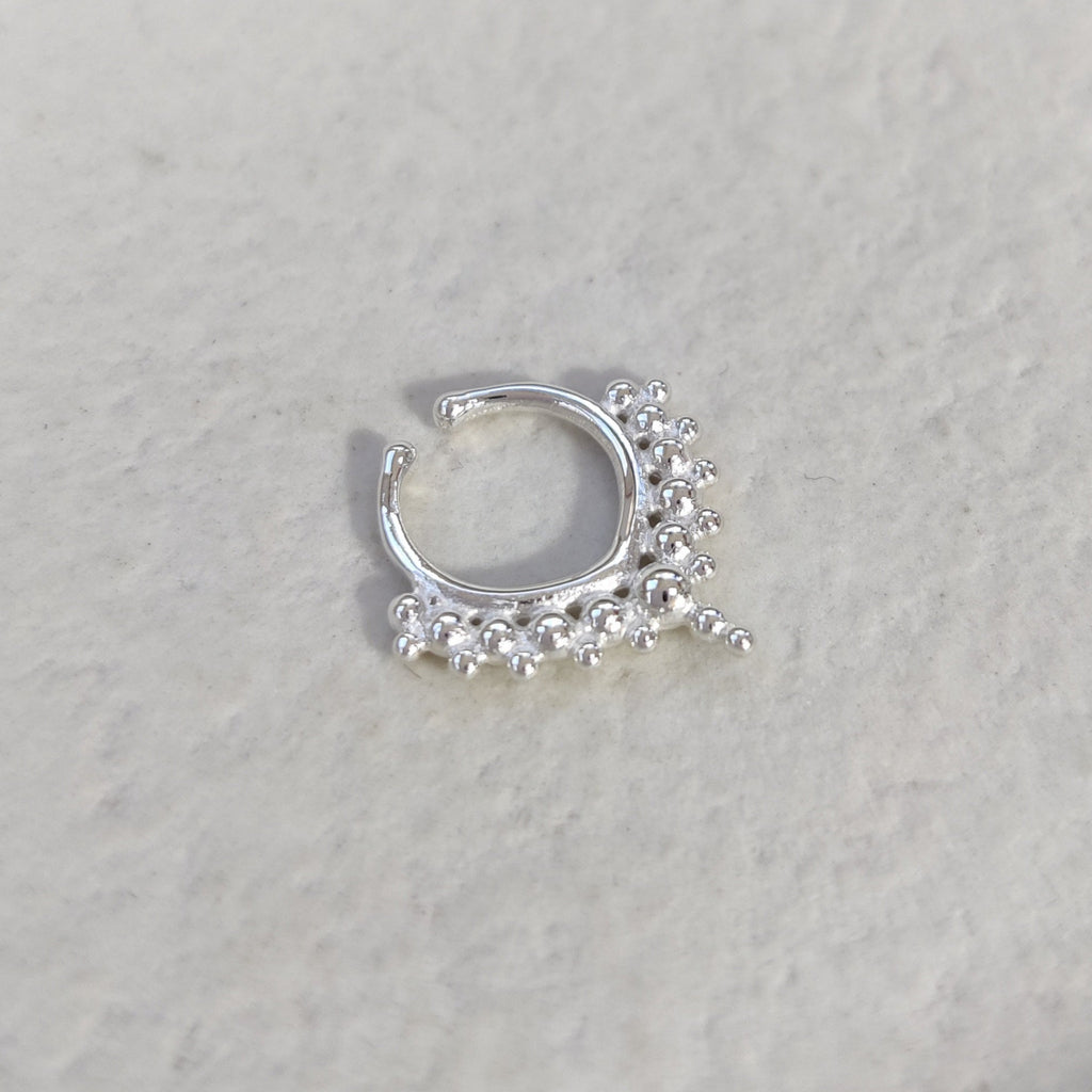 Silver fake septum with V-shape, adorned with small ornamental balls on a light background.