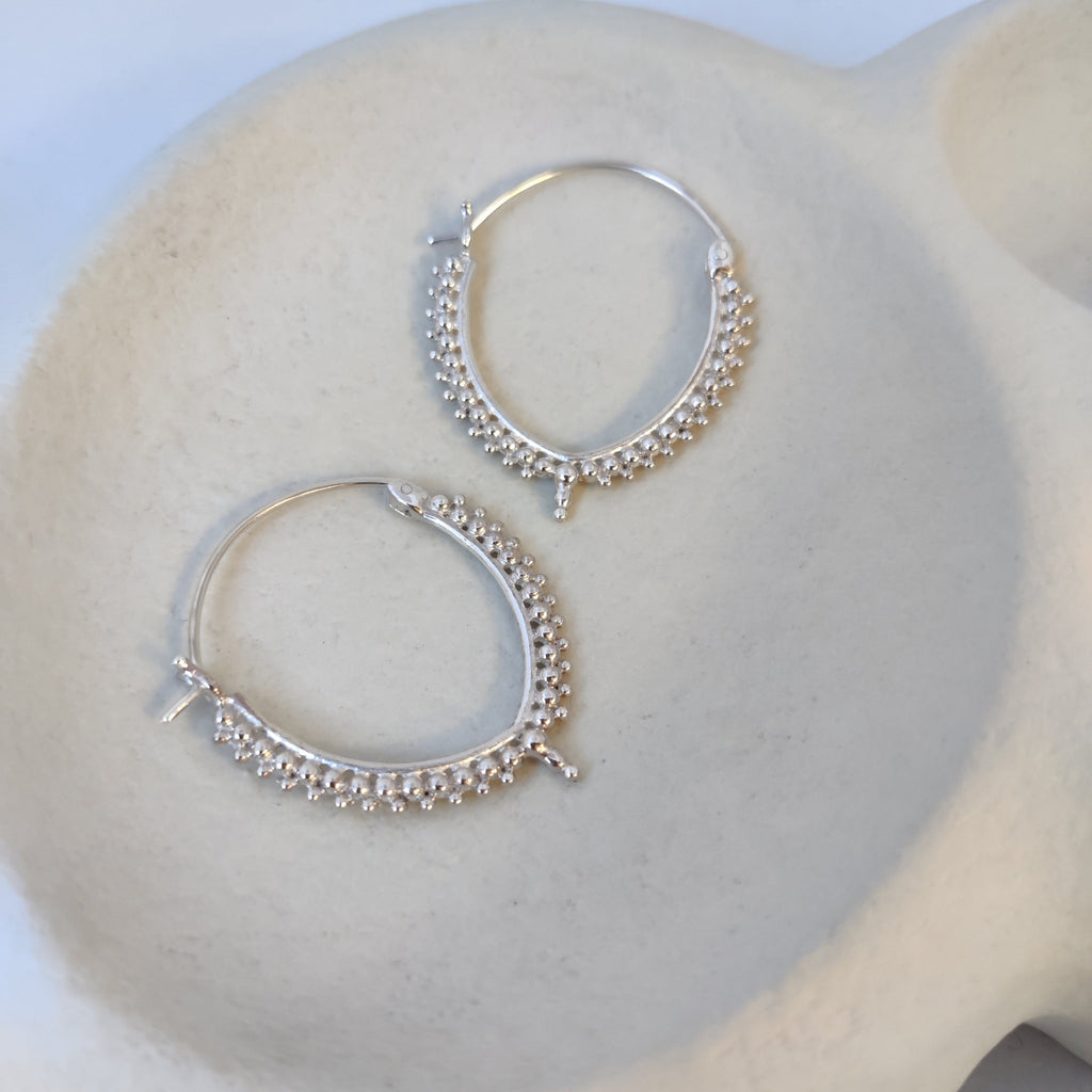 Elegant silver hoop earrings with a subtle V-shape, adorned with delicate dotted details, highlighting their intricate design.