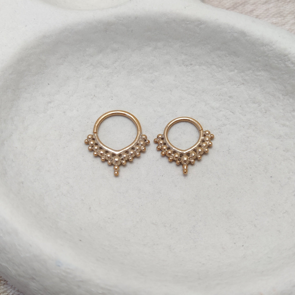 Solid gold septum jewelry, displayed on a jewelry plate.