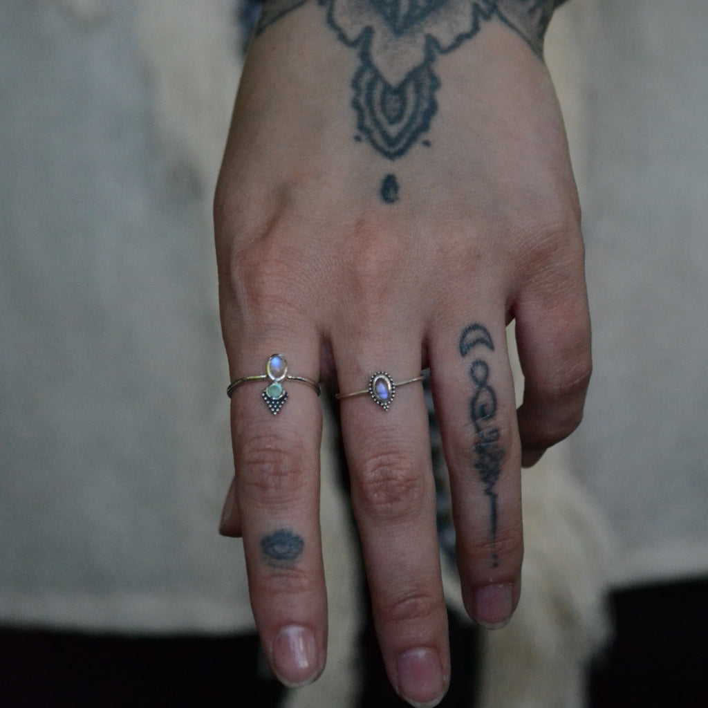 A person's hand displaying two silver rings with moonstone