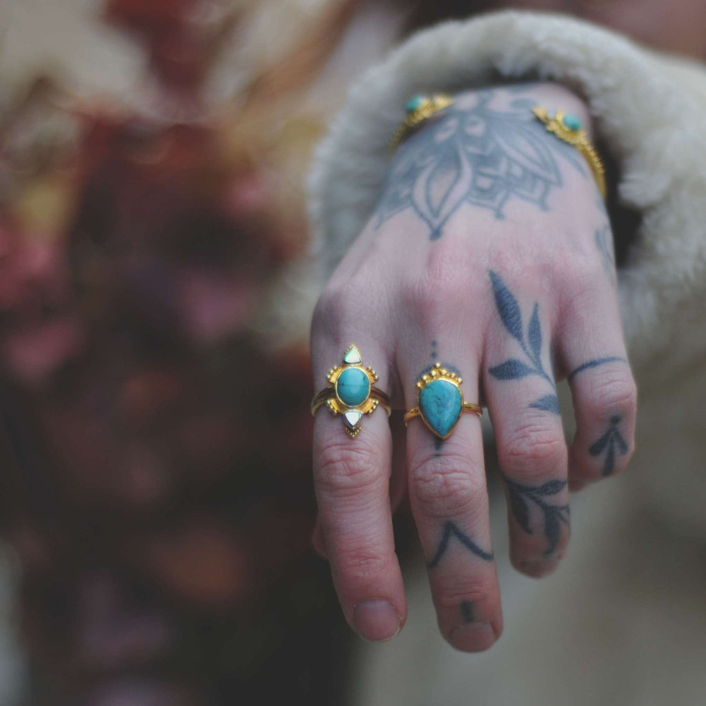 Brass rings with turquise, worn on a hand.