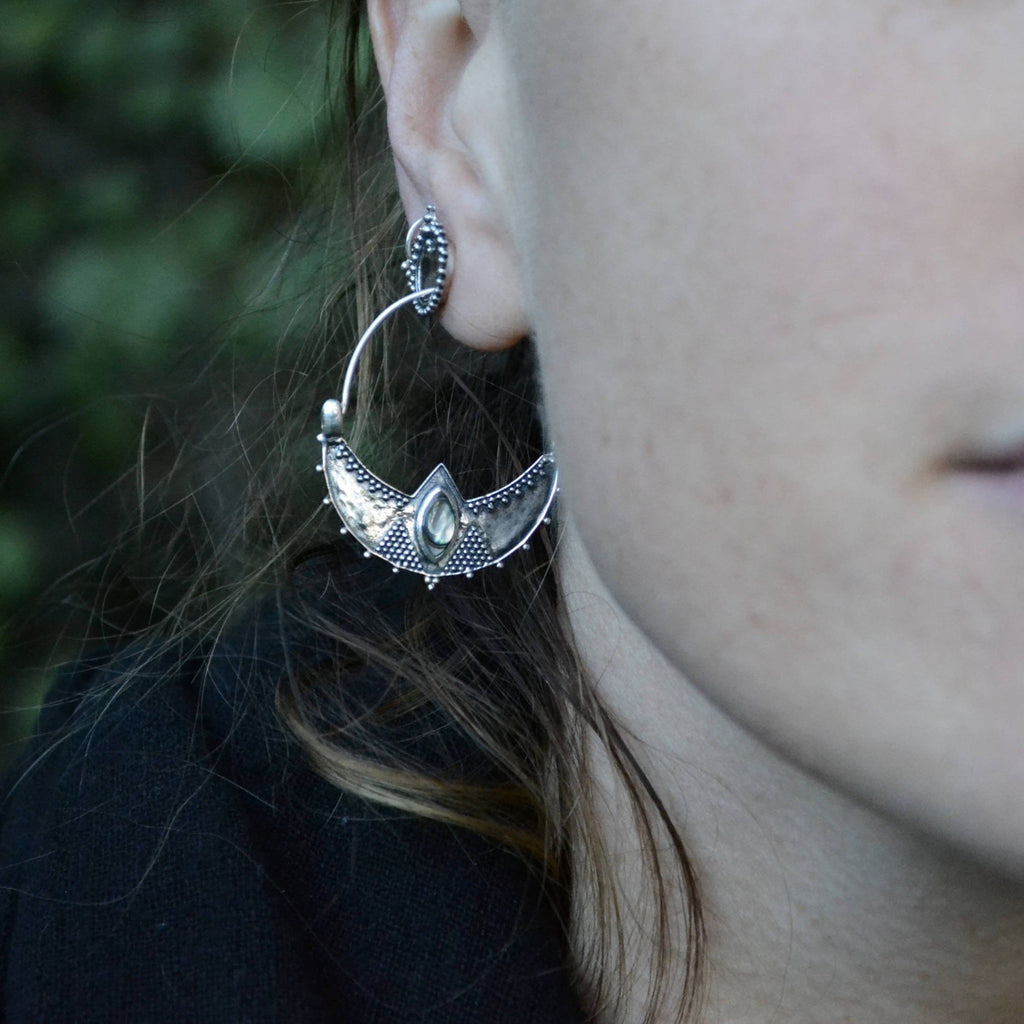 Model adorned with crescent silver earrings with abalone shell.