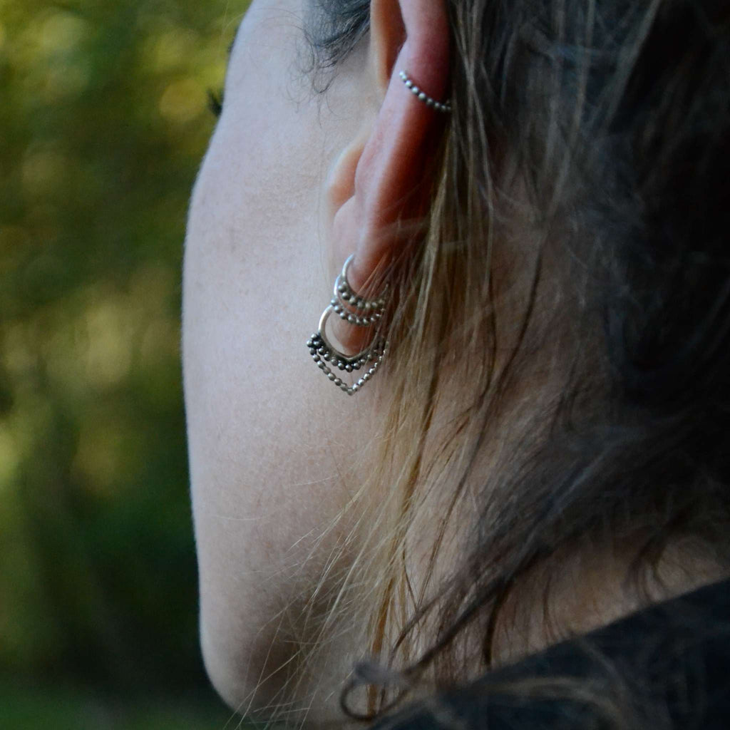 A model wearing dainty silver hoop earrings, captured from the side to showcase their delicate design and intricate details.