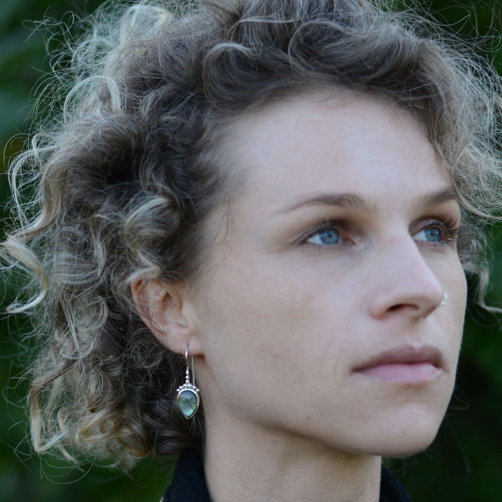 Model wearing silver drop earrings with labradorite.